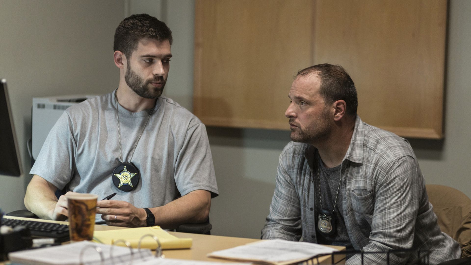 Dos policías de civil están sentados en una mesa hablando