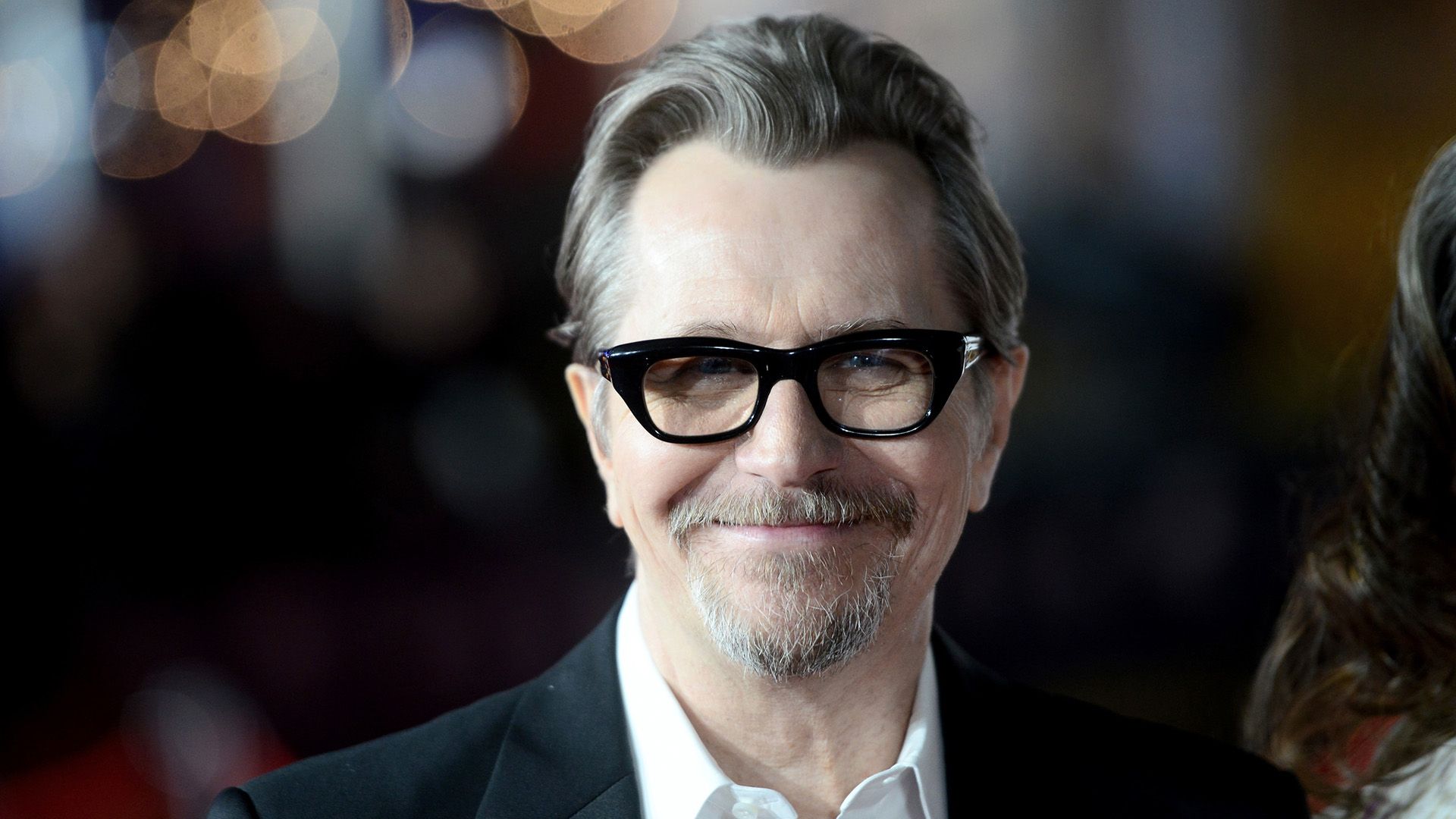 Actor sonriente Gary Oldman con gafas de montura negra