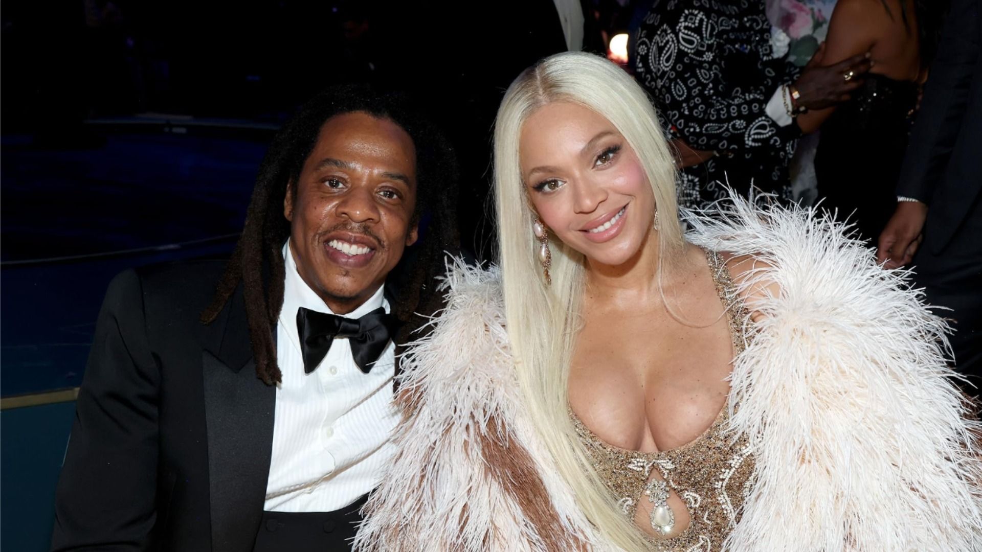 Los artistas Jay-Z y Beyoncé con atuendo de noche miran a la cámara y sonríen