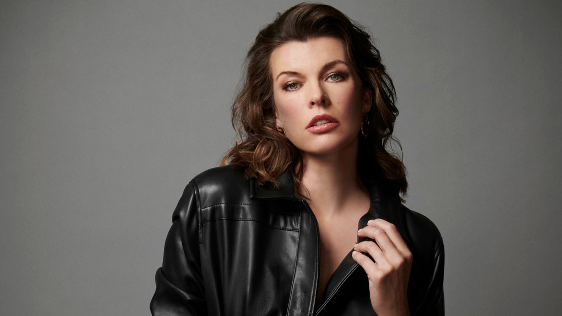 Milla Jovovich in a black leather jacket on a gray background