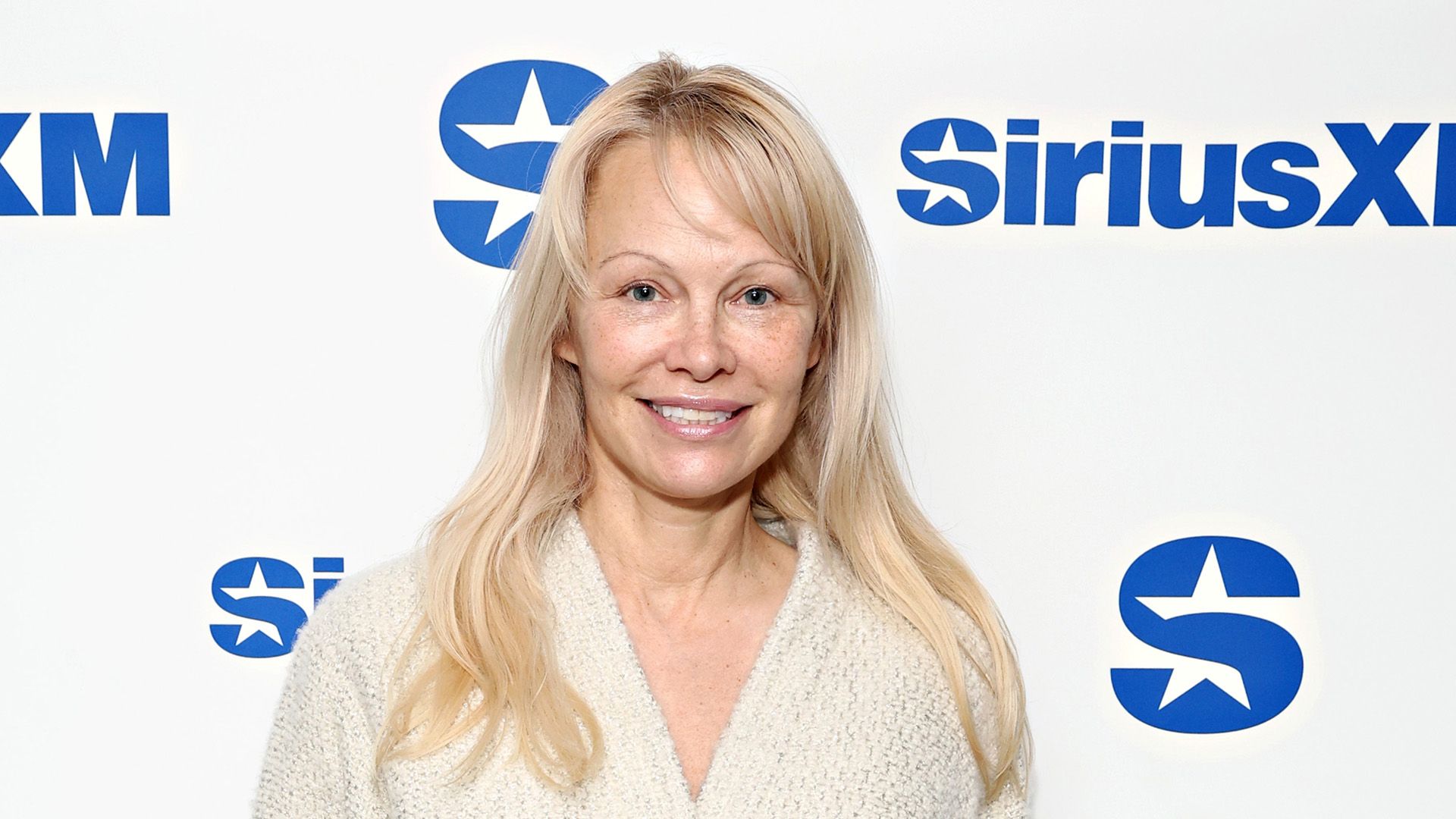 Actriz Pamela Anderson sin maquillaje, vestida con un suéter beige