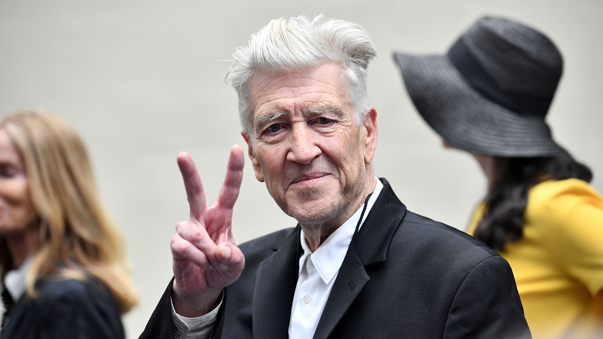 Director David Lynch muestra un signo de V con sus dedos y sonríe