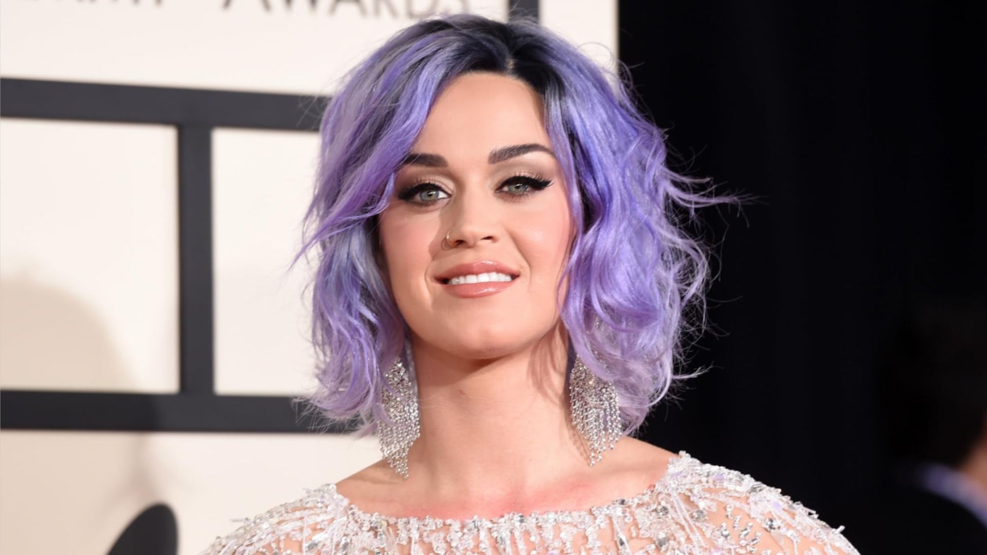 La cantante Katy Perry en un vestido brillante sonríe a la cámara contra un fondo en blanco y negro