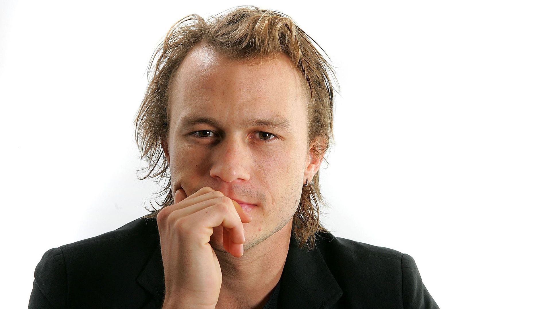 Actor Heath Ledger con una chaqueta negra sobre un fondo blanco