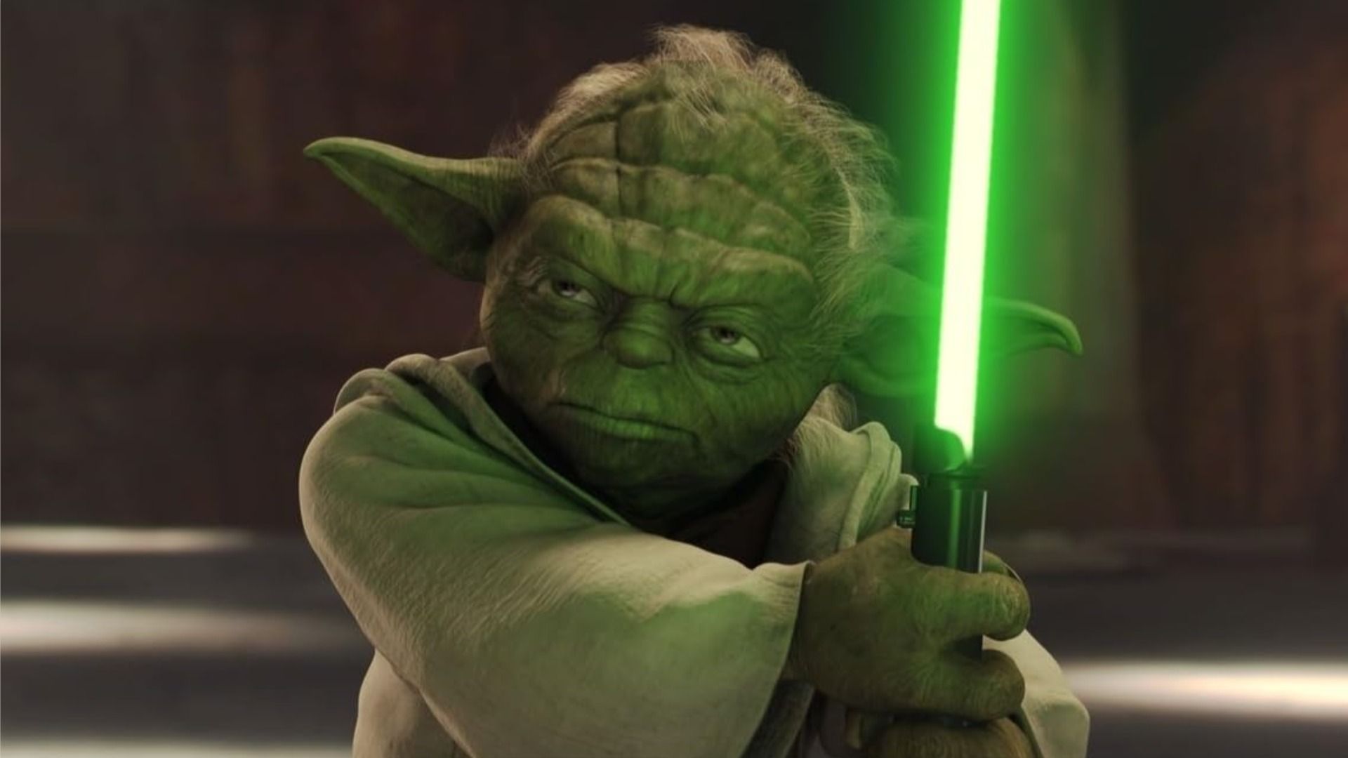 El maestro Yoda sostiene un sable de luz y mira severamente hacia un lado contra un fondo marrón