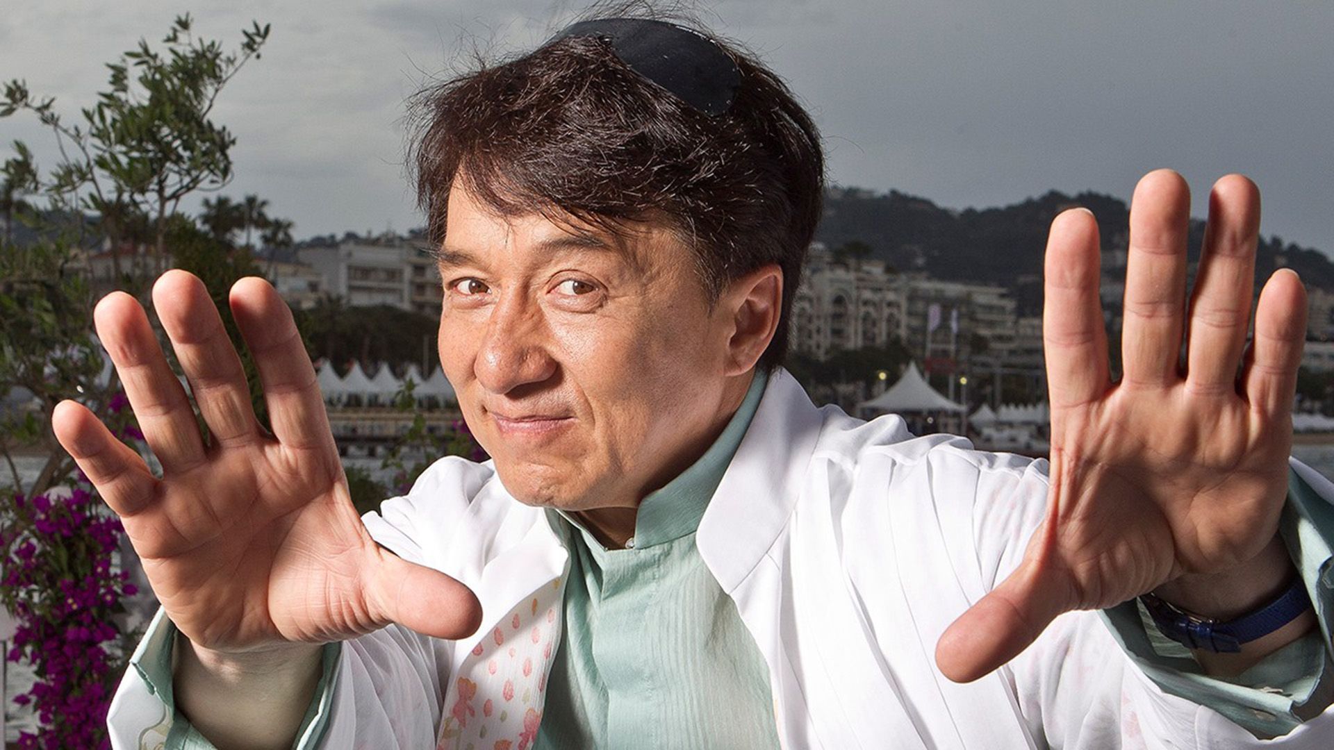 Jackie Chan sonriendo con las manos extendidas