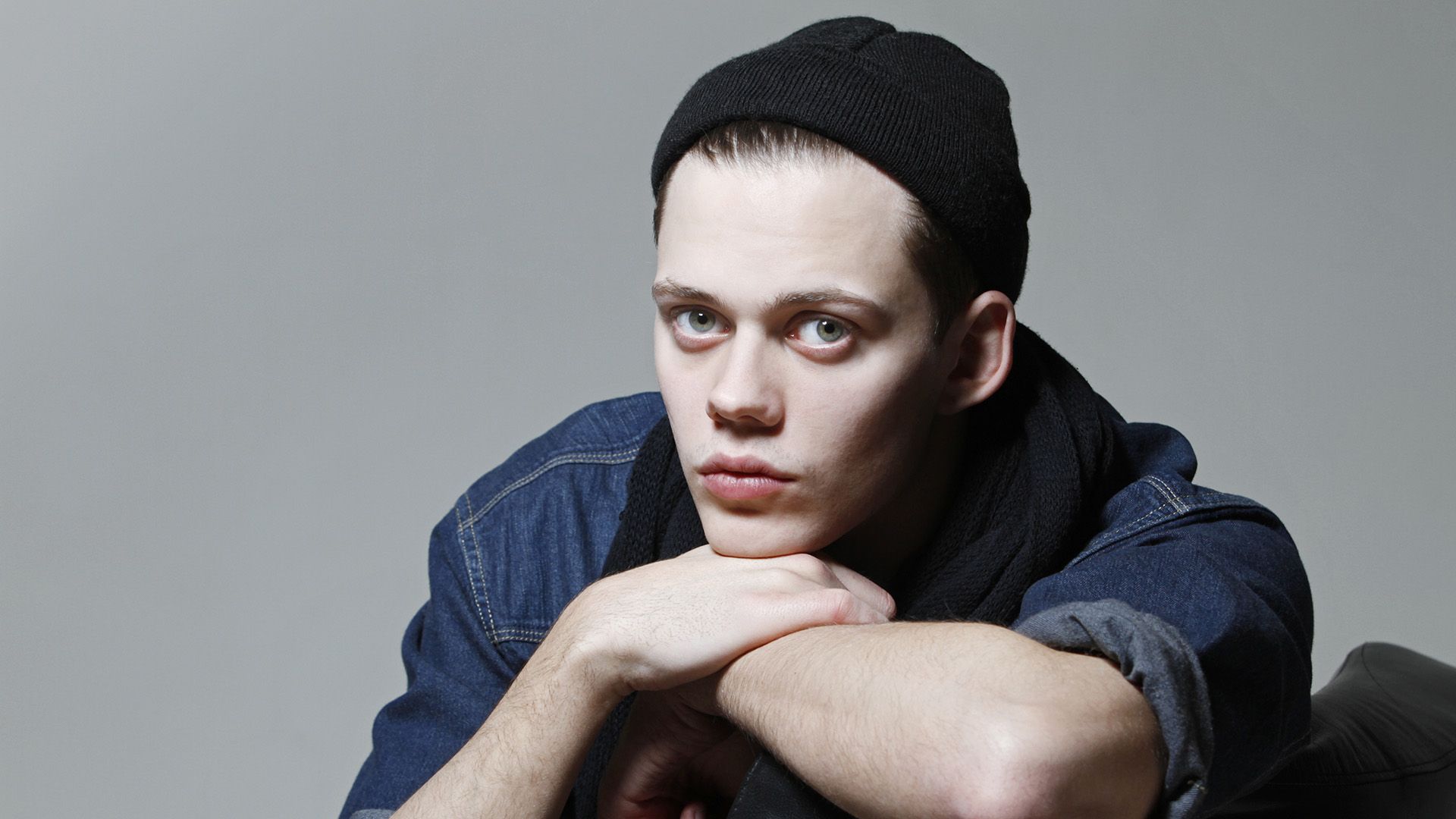 Actor Bill Skarsgard en un sombrero negro contra un fondo gris