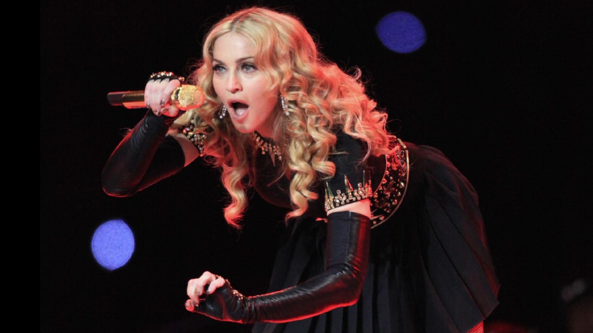 Madonna canta en el micrófono, inclinándose hacia adelante