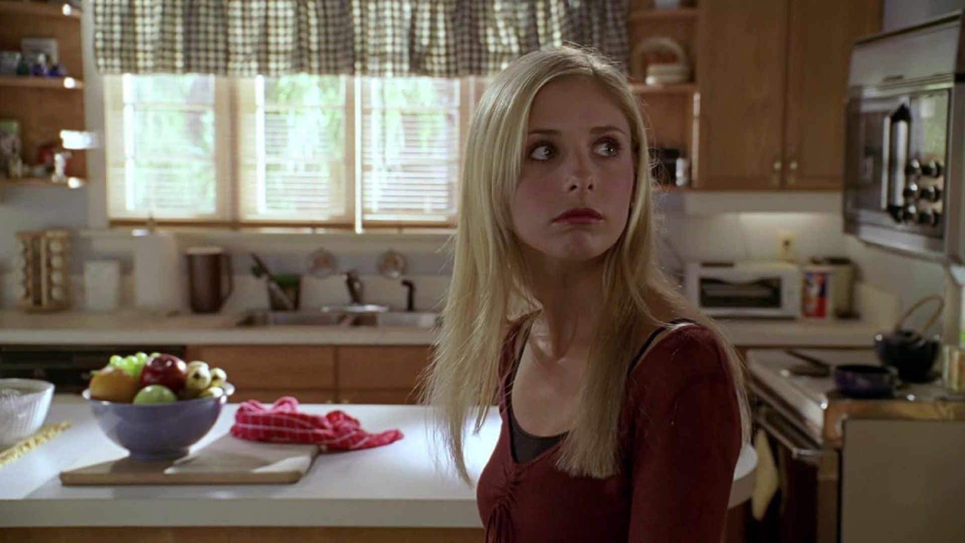 Sarah Michelle Gellar como Buffy mira hacia un lado, juzgando en la cocina