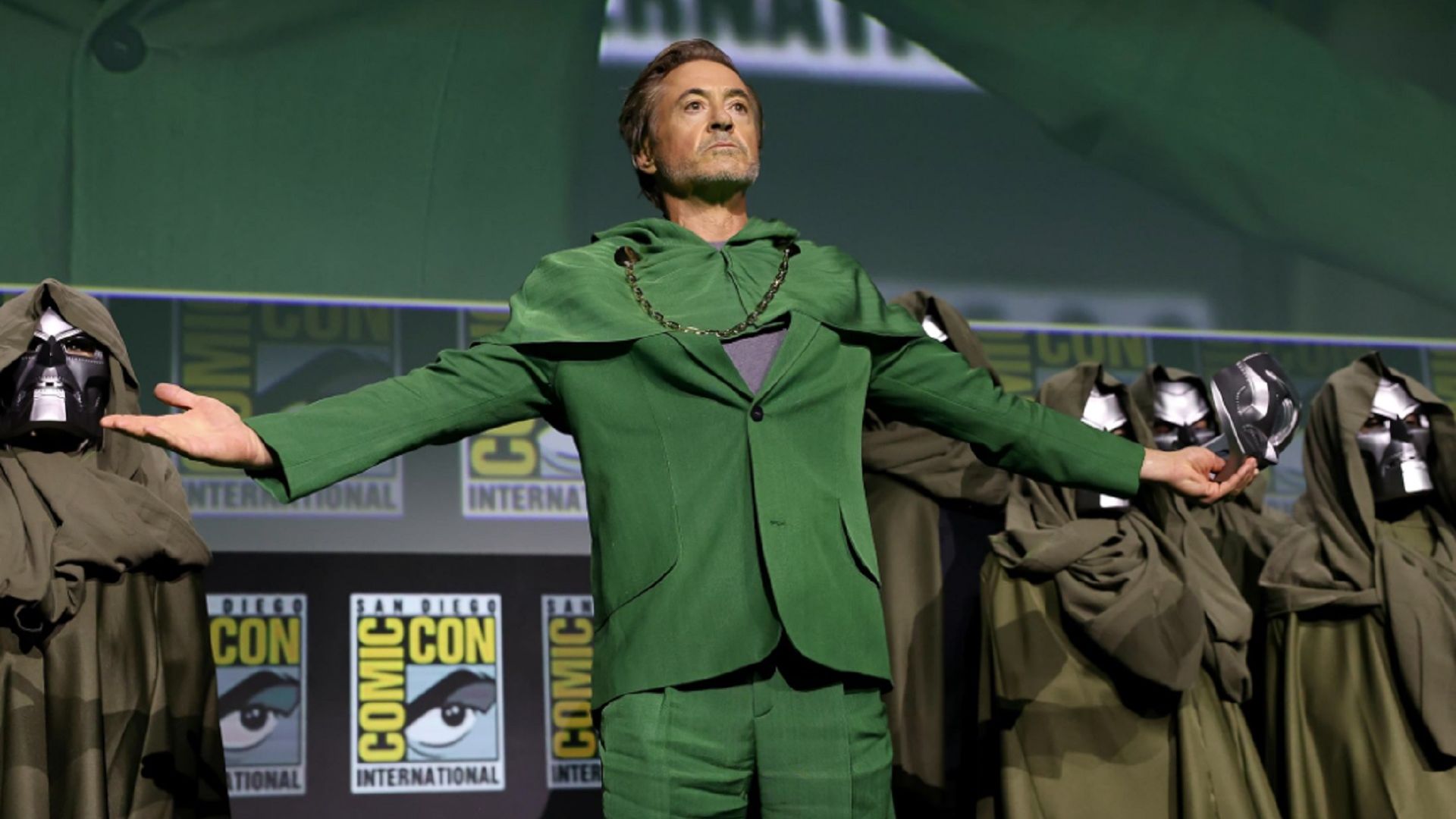 Robert Downey Jr. en un traje verde en el escenario con los brazos extendidos