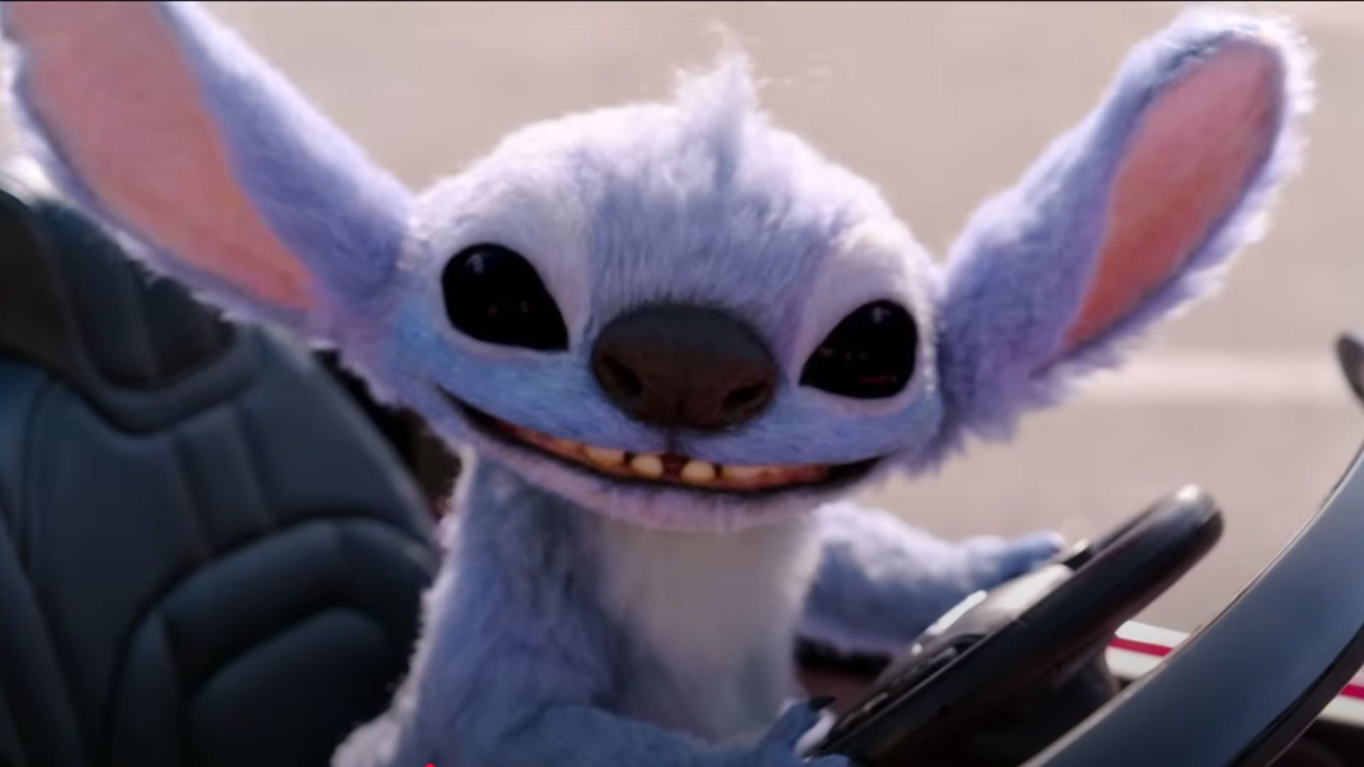 El alienígena azul Stitch se sienta al volante de un auto pequeño y sonríe