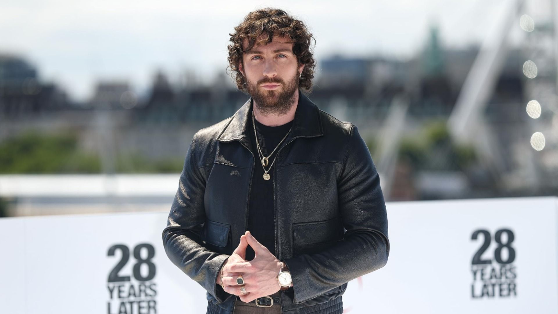 El actor Aaron Taylor-Johnson con chaqueta de cuero negro sobre un fondo urbano desenfocado