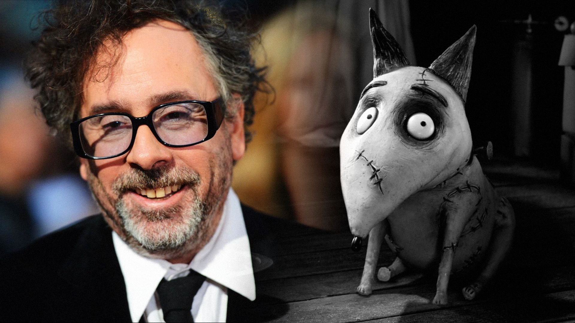 Director Tim Burton con chaqueta negra y gafas, con un perro gris a su lado