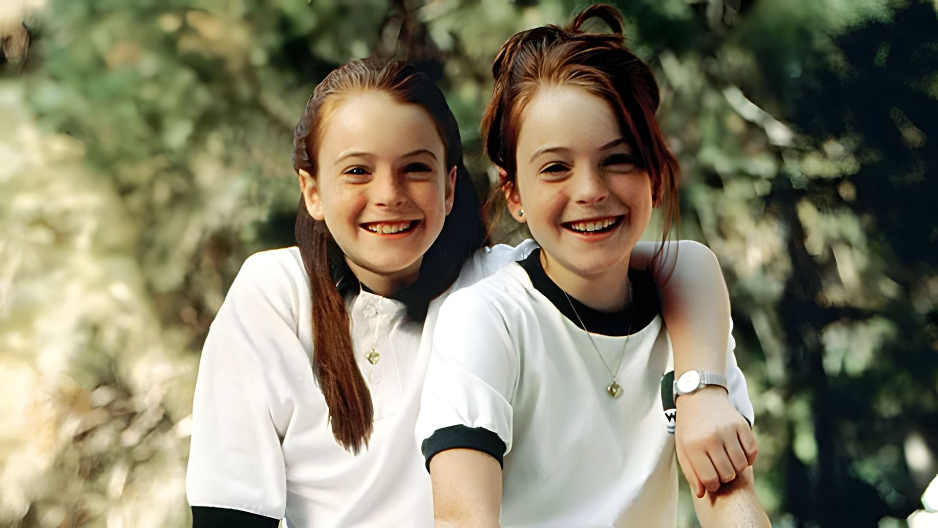Lindsay Lohan como gemelas, ambas vistiendo camisetas blancas contra un fondo verde