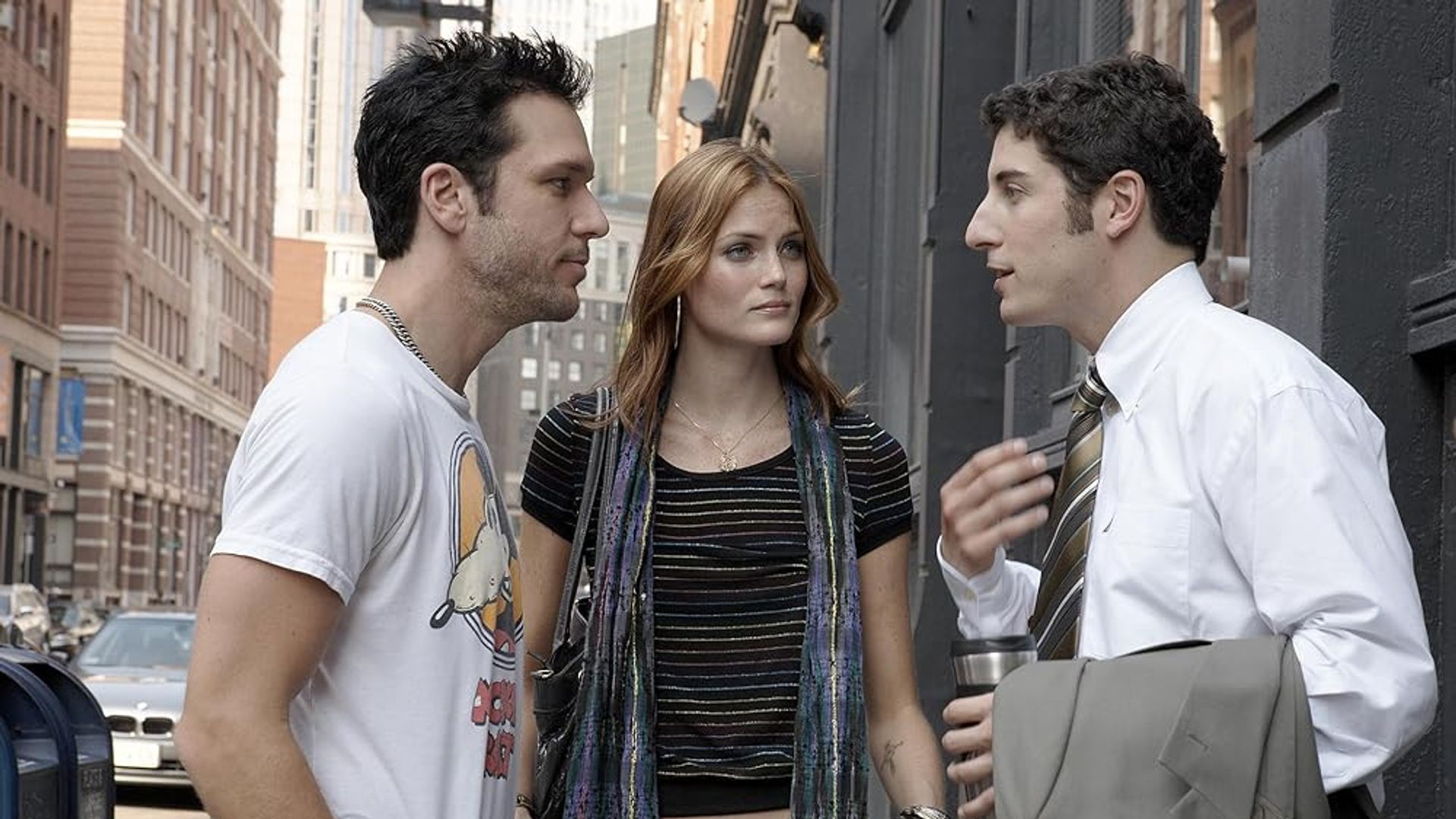 Dos hombres y una mujer hablando en la calle entre edificios de la ciudad