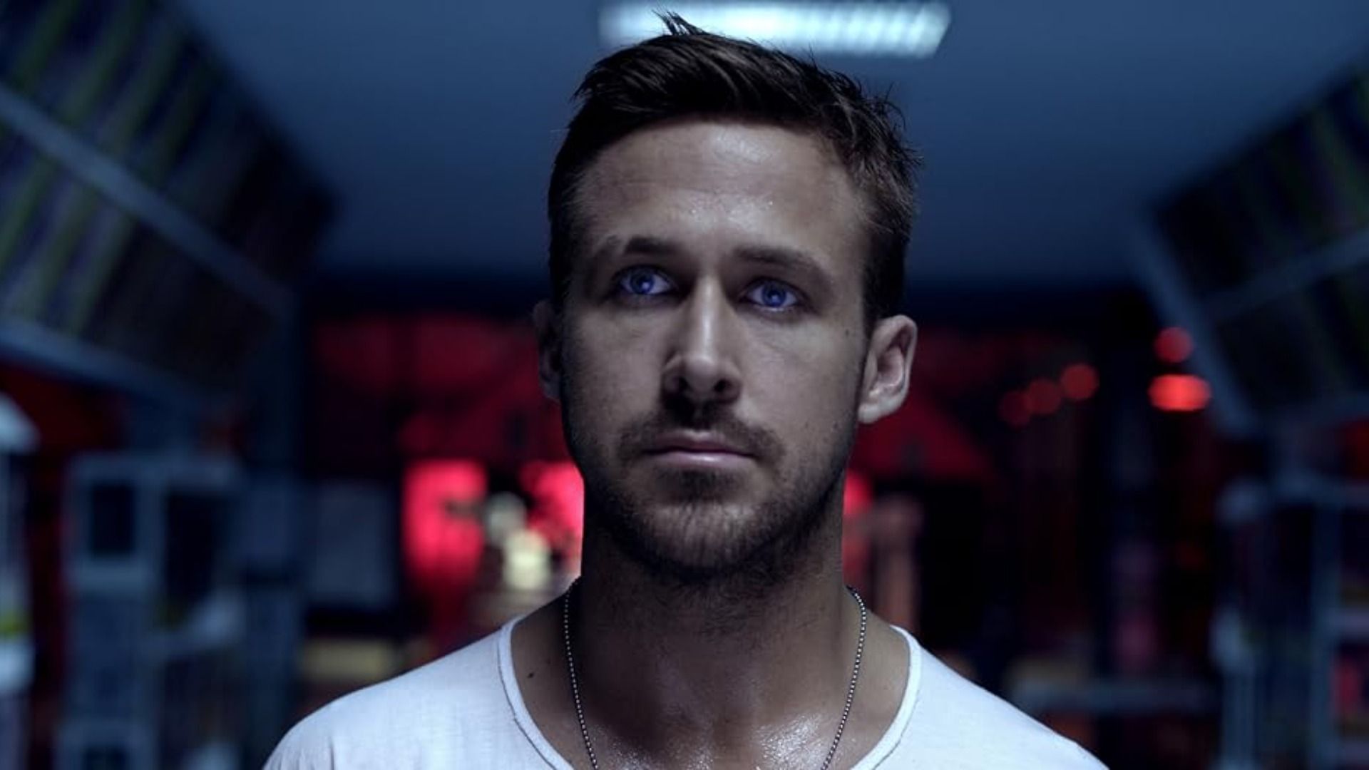 El actor Ryan Gosling con camiseta blanca sobre un fondo difuminado