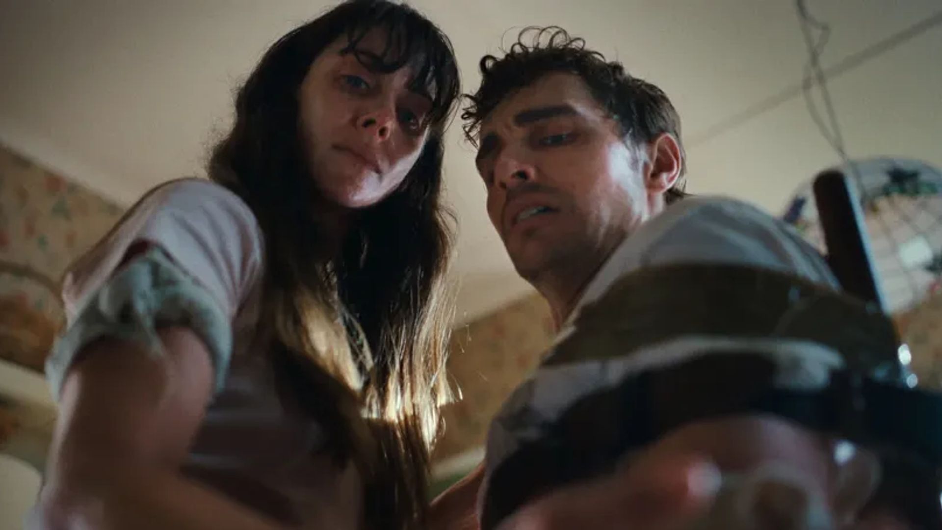 Alison Brie y Dave Franco miran a la cámara con expresiones preocupadas, filmados desde un ángulo bajo